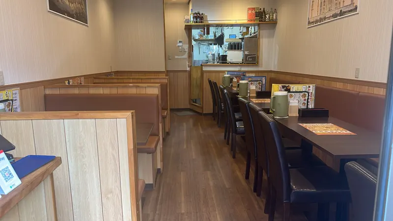 木目の腰壁とブラウンのボックス席が並ぶ店内